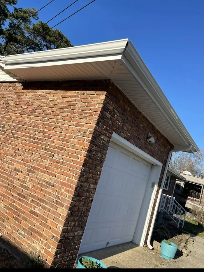 Finished white soffit and gutters on brick garage after replacement