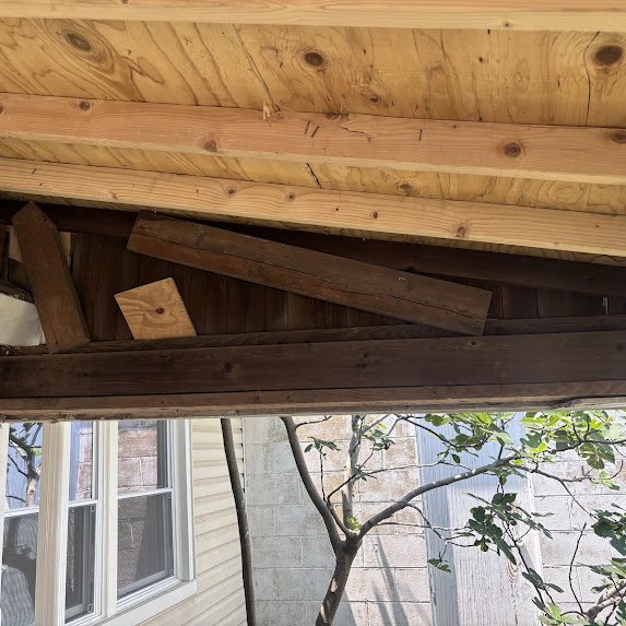 Old porch overhang in Bradley Beach with mixed aged wood materials before rebuild