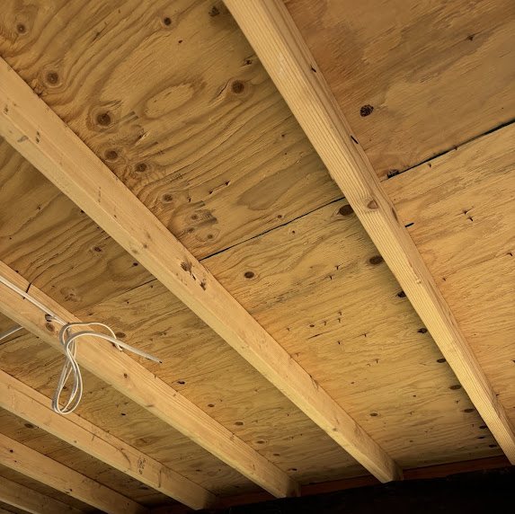 Underside of new plywood roof decking and joists on a rebuilt overhang