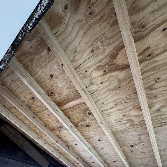 New plywood decking and rafters on a rebuilt porch overhang