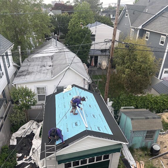 Crew members working on a roof covered in GAF Deck-Armor synthetic underlayment