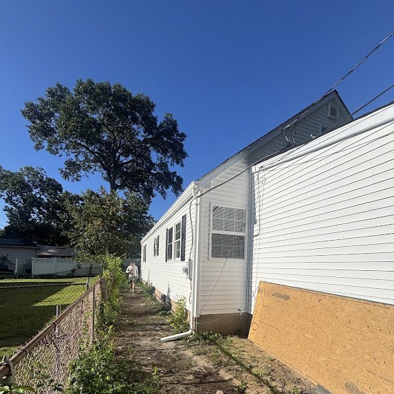 White downspout with an extension at grade carrying water away from a new home's foundation
