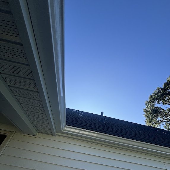 View up along a new white gutter with vented soffit and roof edge