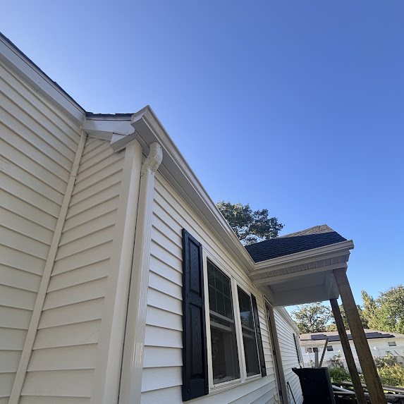 White 2x3 downspout at the porch corner of a new home with black shutters
