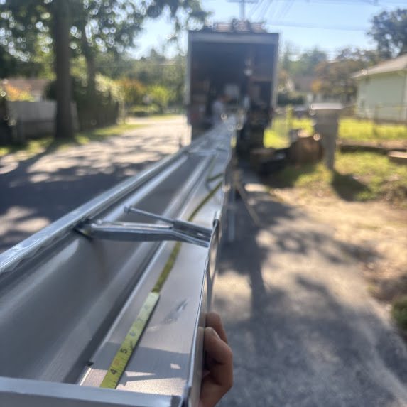 Seamless white 5-inch K-style gutter being formed off a box truck in the street in Browns Mills NJ