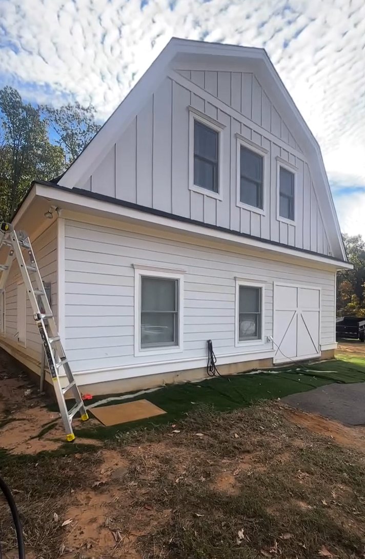 Renovated white barn-style home with a board-and-batten gambrel gable in Colts Neck NJ before gutters