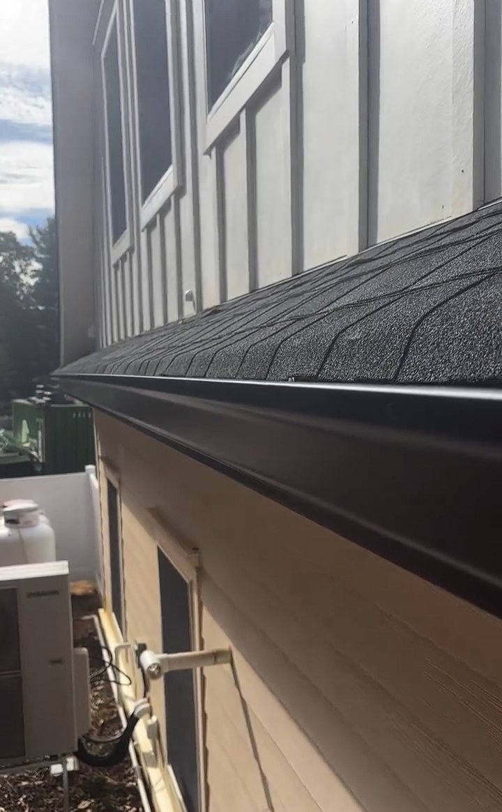 Black 6-inch seamless gutter installed along a roof edge below board-and-batten siding in Colts Neck