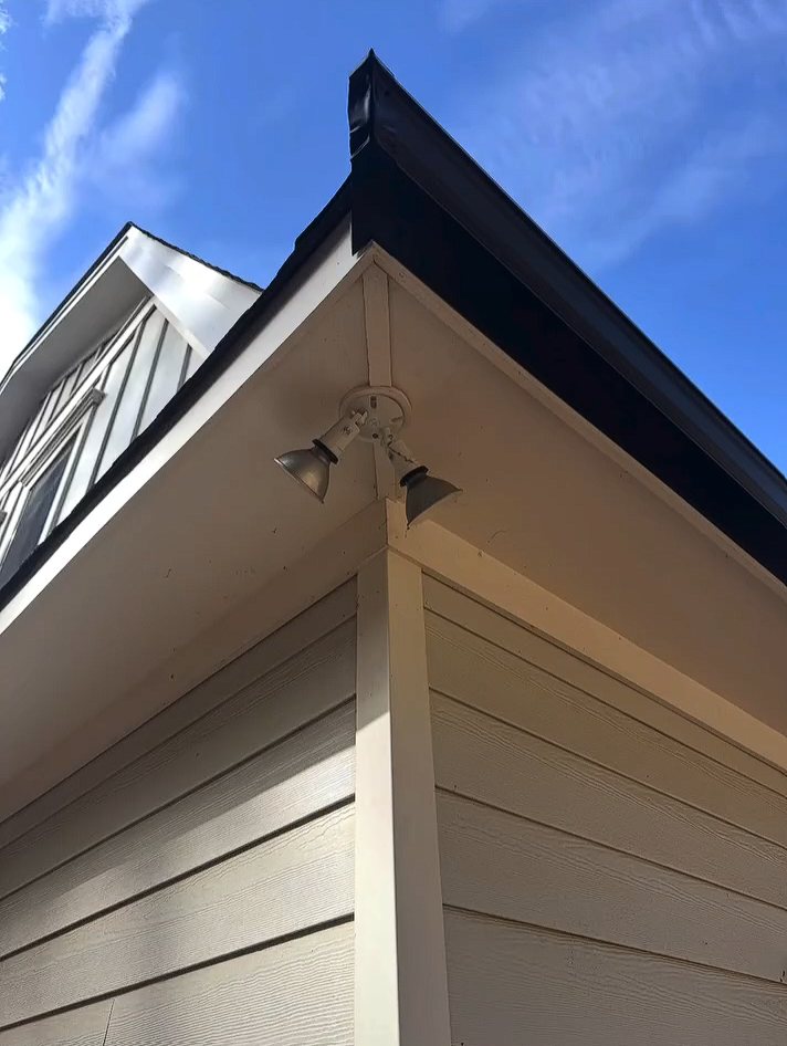Mitered corner of a black K-style gutter above white soffit and siding on a Colts Neck home