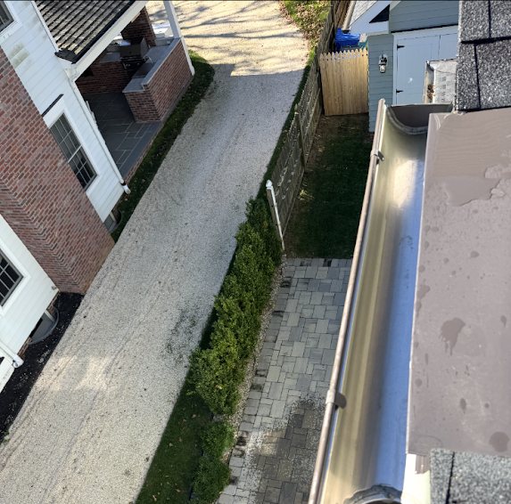 Freshly cleaned half-round gutter above a side yard and paver walkway in Fair Haven NJ