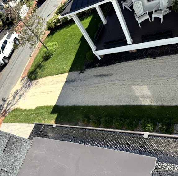 Stainless steel gutter guard fastened along a gutter above a front porch and lawn in Fair Haven