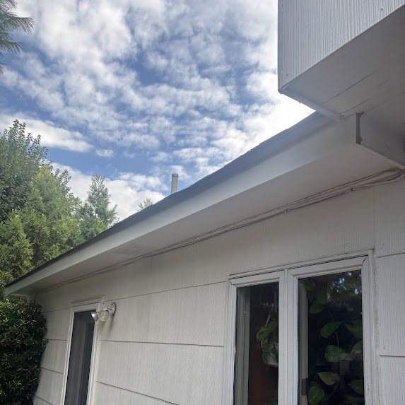 Freshly wrapped white aluminum fascia along a roofline before gutter installation