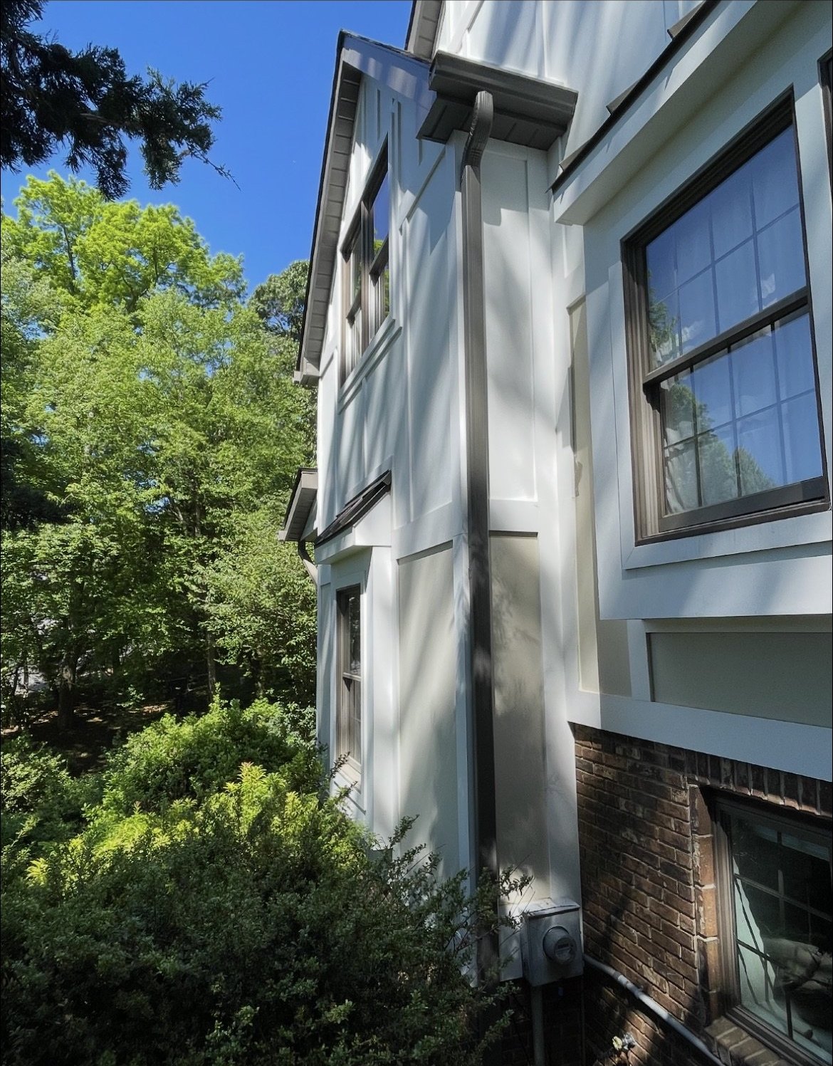 White board-and-batten Holmdel home with 6-inch colored gutters and color-matched downspout