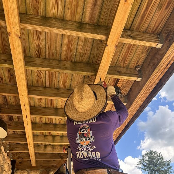 Gutter Bandits crew member installing soffit panels under the deck