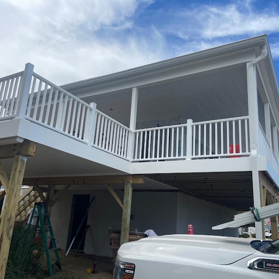 White gutter and downspout at the corner of an elevated porch on a new home