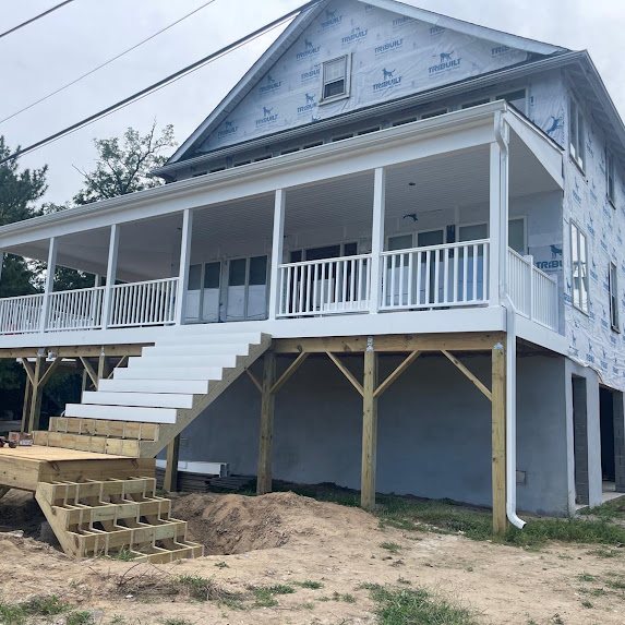 Elevated new construction shore home in Manasquan NJ with a wraparound porch and new white 6-inch K-style gutters
