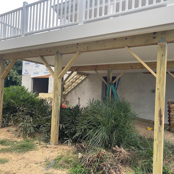 View under an elevated deck showing the beadboard drainage soffit and pressure-treated posts