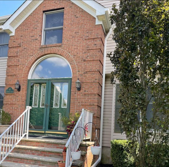Brick front entry with green double doors and white trim on a Marlboro NJ colonial