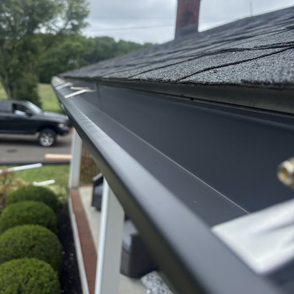 Close-up along a new black 5-inch seamless gutter at the roof edge