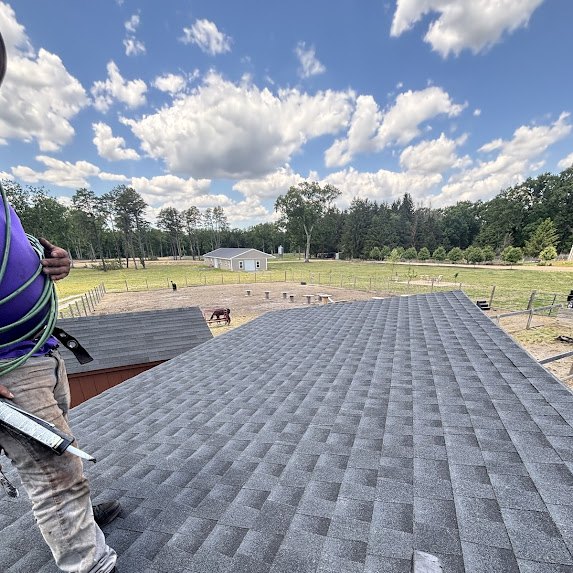 Crew member on the ridge of a newly shingled roof at a Millstone Township cattle ranch