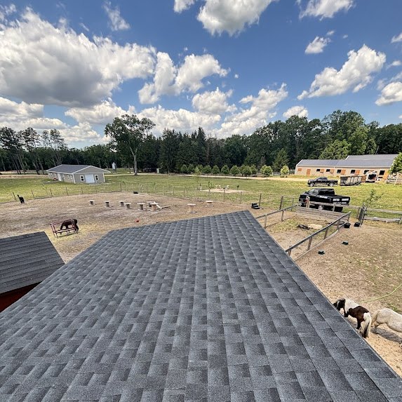 View from the ridge of a freshly shingled charcoal roof at a cattle ranch in Millstone Township, pastures and barn in the distance