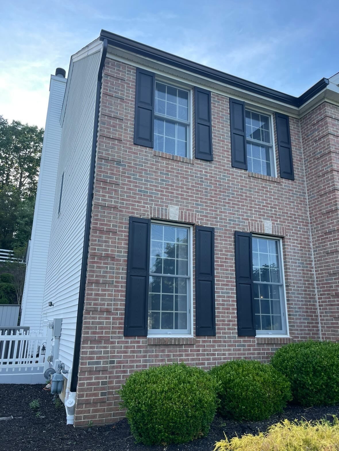 Black seamless gutter line at the corner of a brick colonial