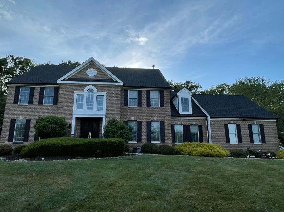 Large brick colonial in Millstone Township with new black seamless gutters and black shutters