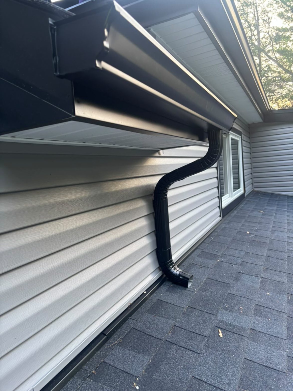 Black downspout with a clean offset bend against the house