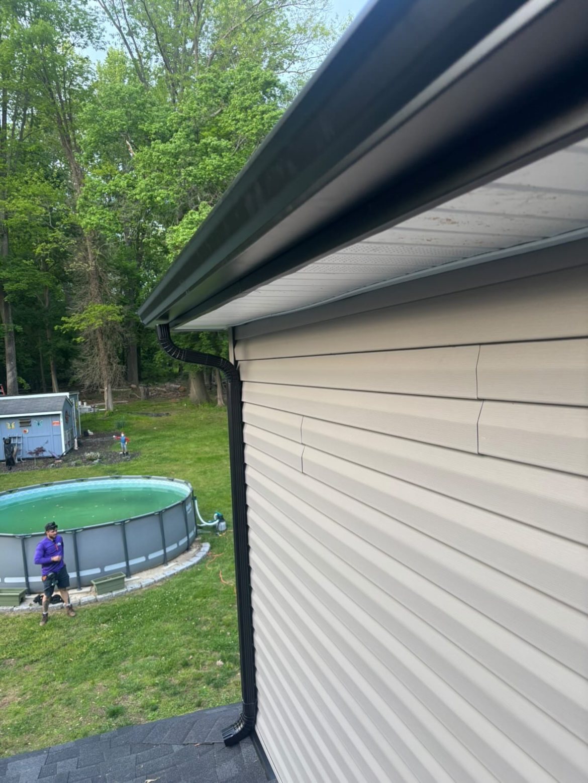 Black seamless gutter line running along the pool yard side of the home