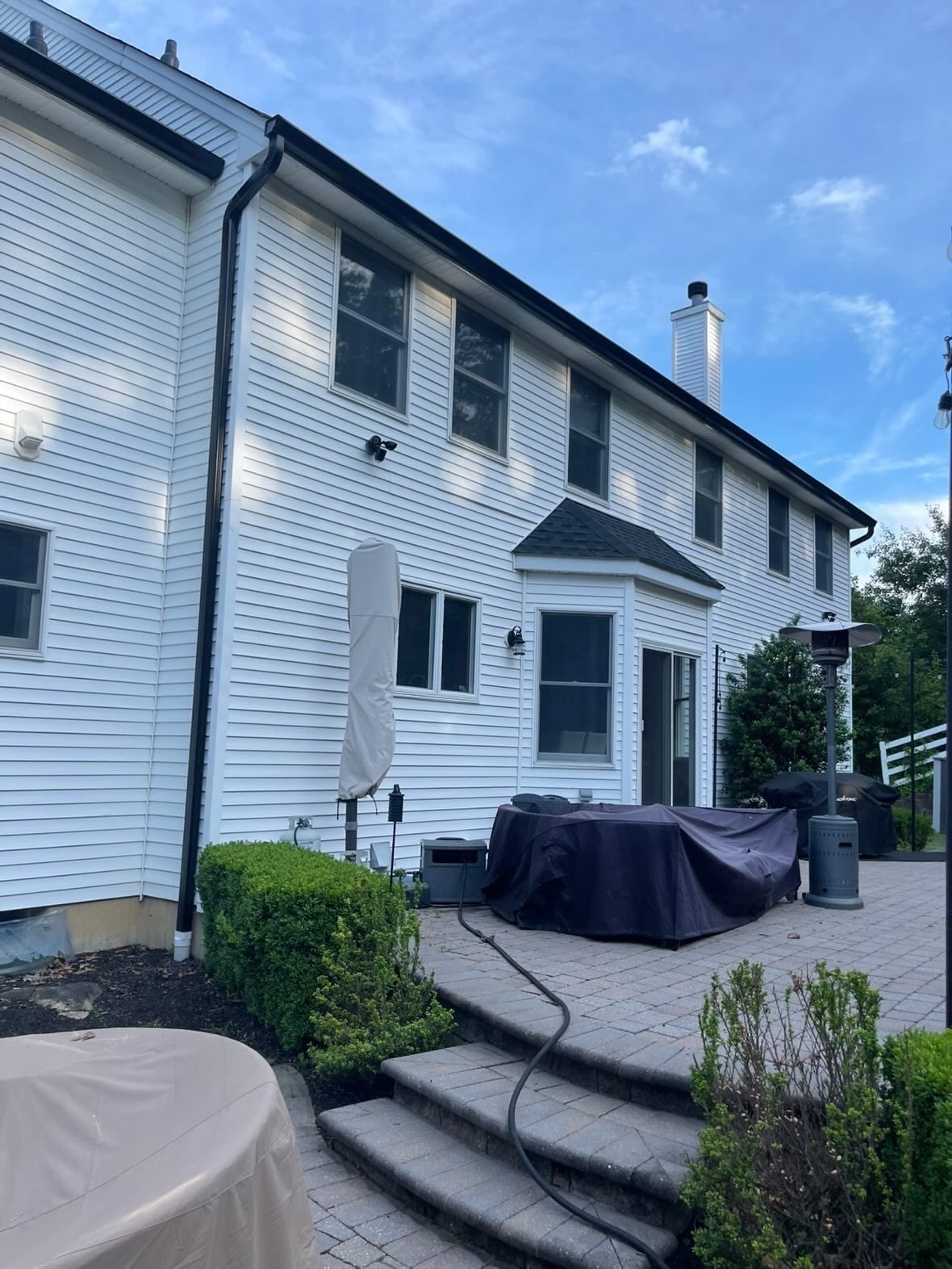 Black gutter line above a patio on a white colonial
