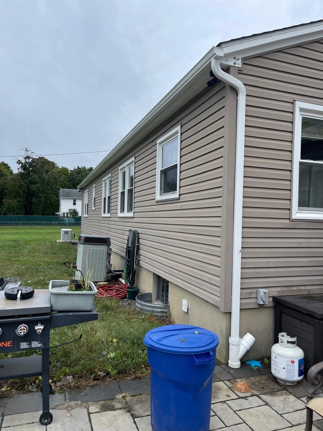 White gutter and downspout at the rear corner of a tan-sided ranch in Millstone NJ