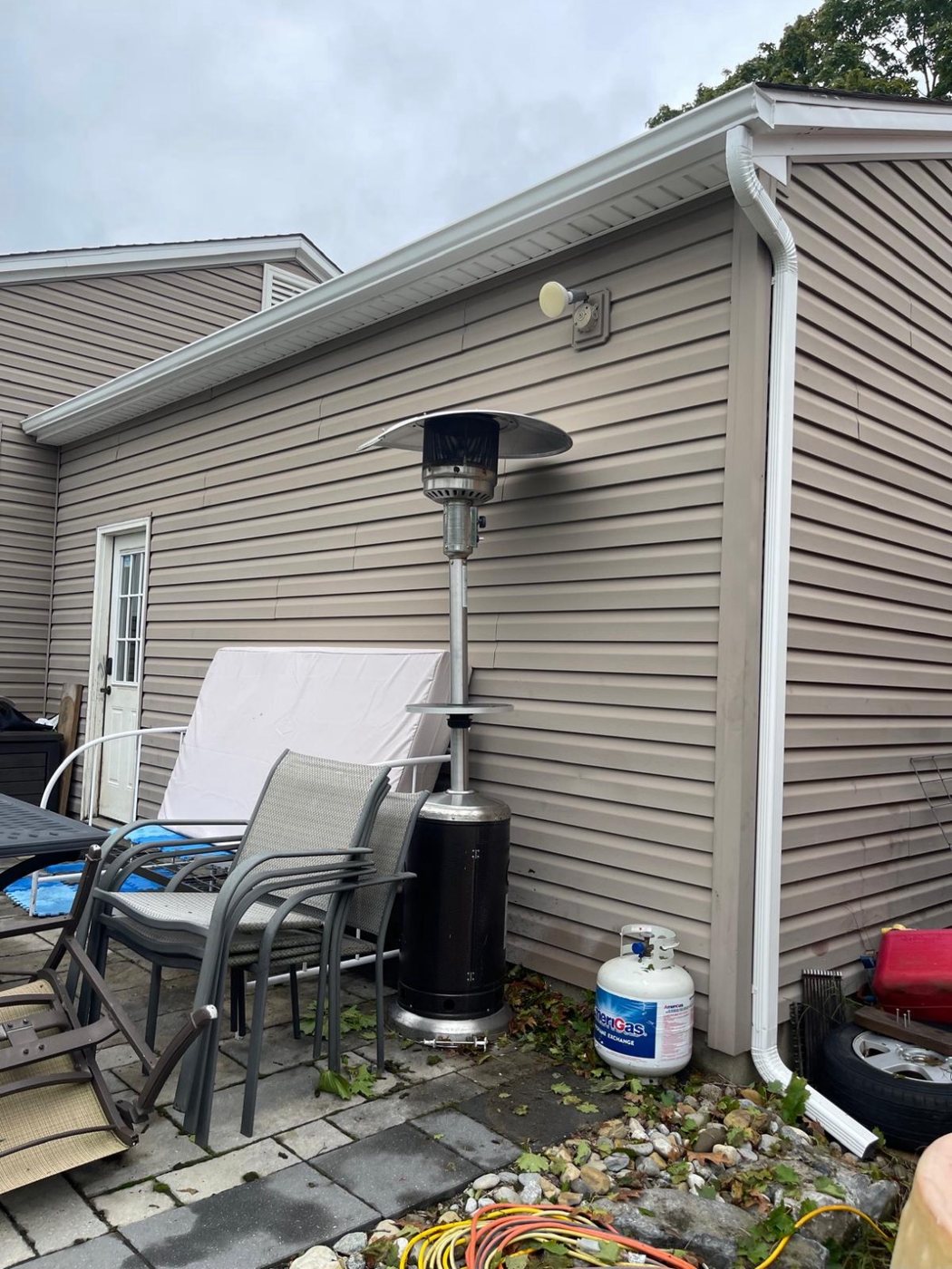White 2x3 downspout at the back corner of a Millstone Township home beside the patio