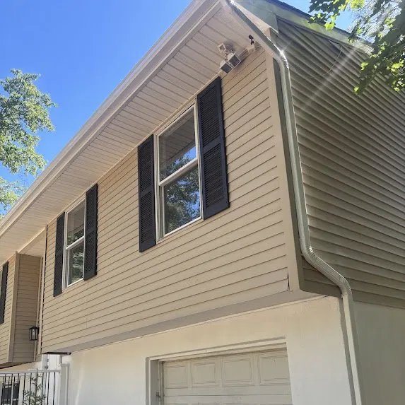 Clean white gutter line against light siding and black shutters