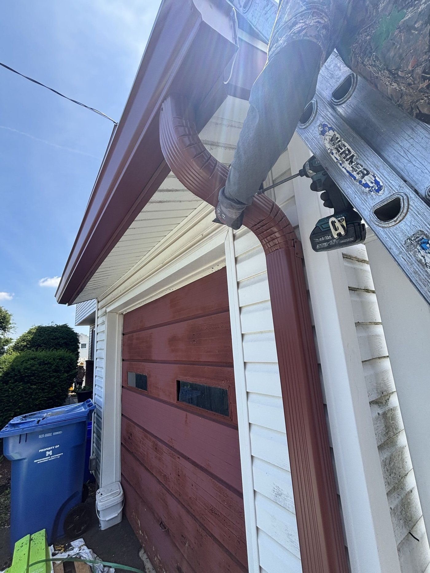 Installer securing a Scotch Red downspout on a garage in Old Bridge
