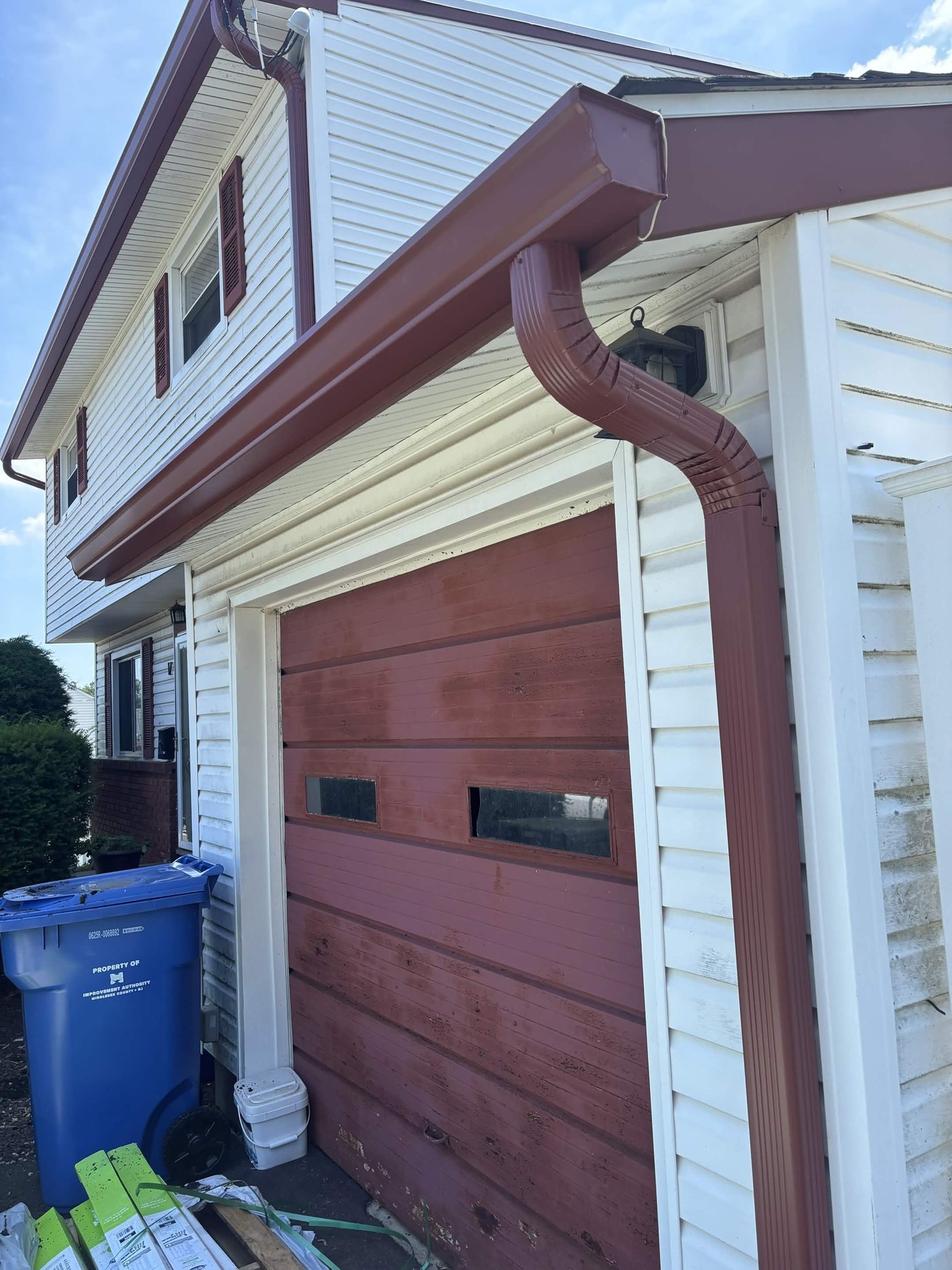 Scotch Red gutter and downspout beside a barn-red garage door