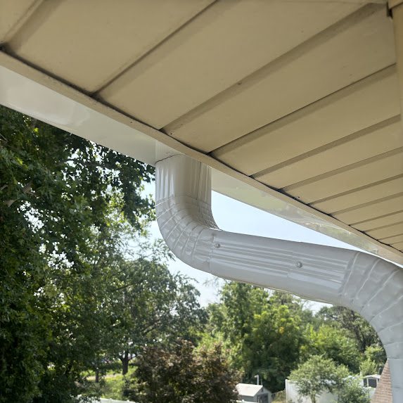 White 3x4 downspout elbow under a porch soffit in Riverside NJ
