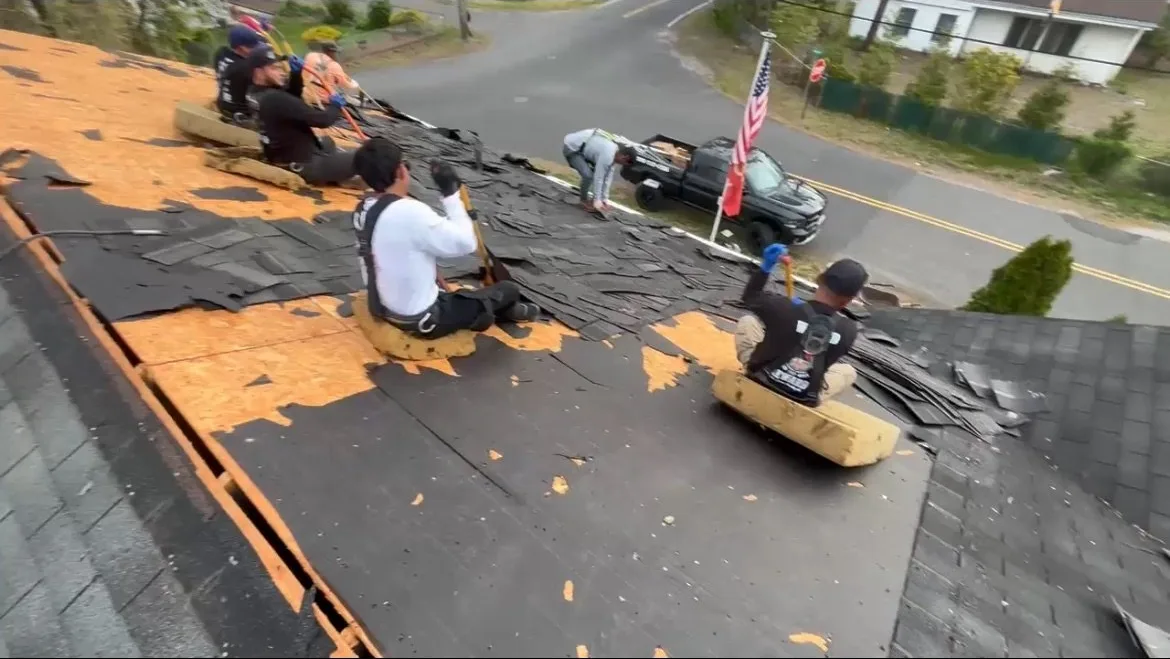 Crew on the roof during tear-off — exposed deck visible