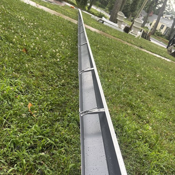 New white seamless K-style gutter run laid on the lawn with hidden hangers