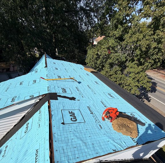 GAF synthetic underlayment covering a roof ridge with a leaf blower resting on it